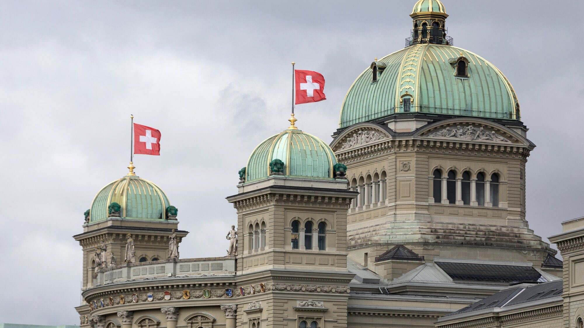 Les coupoles du Palais fédéral à Berne, surmontées de drapeaux suisses