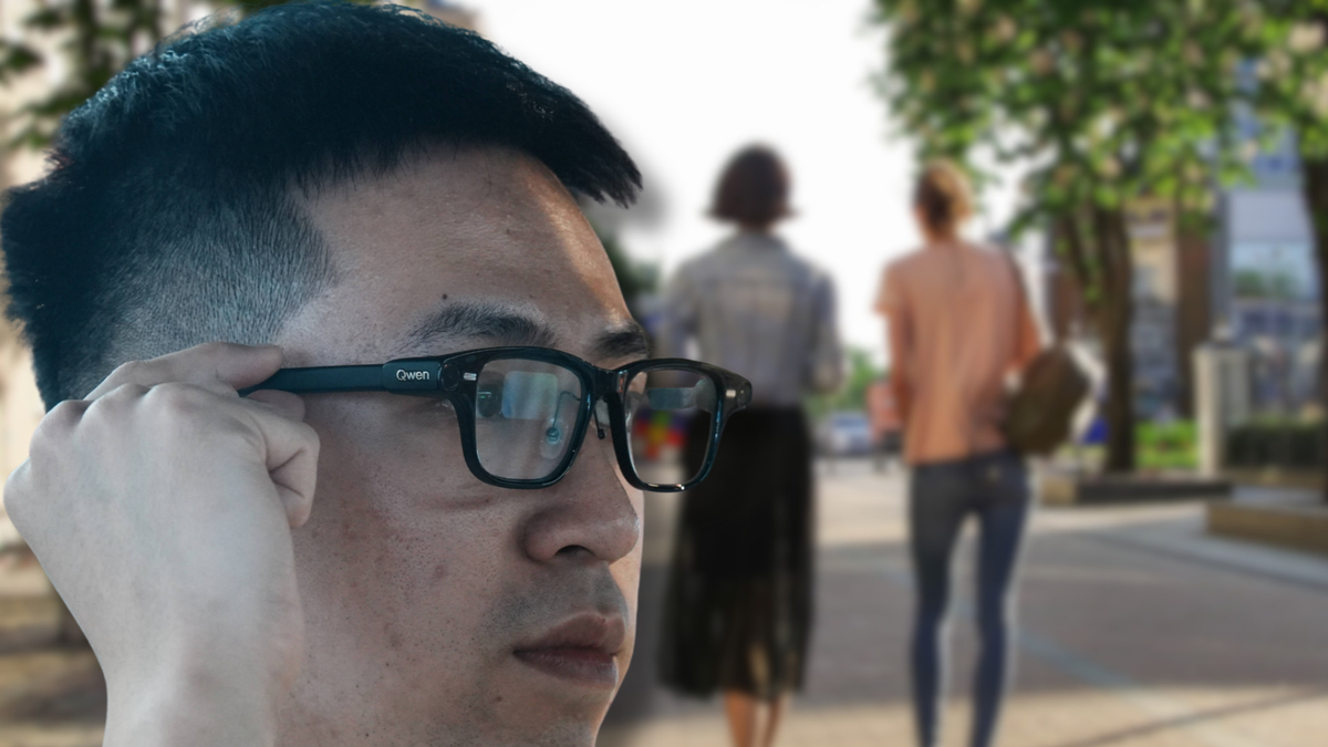 Un homme règle ses lunettes connectées d’un geste sur la branche, dans une rue où marchent deux passants